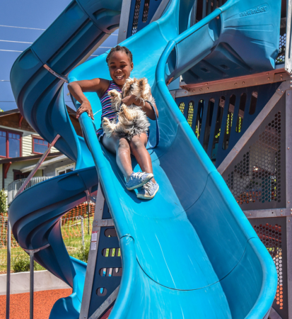 young girl going down blue playground slide