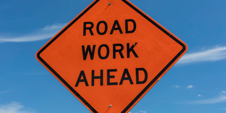 orange road sign with the text road work ahead