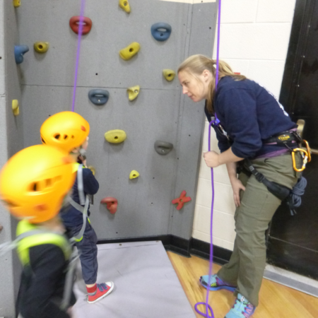 Christine Elyseev teaching two children at climbing wall