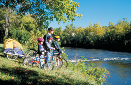 man and three children on bicycles near the riverside