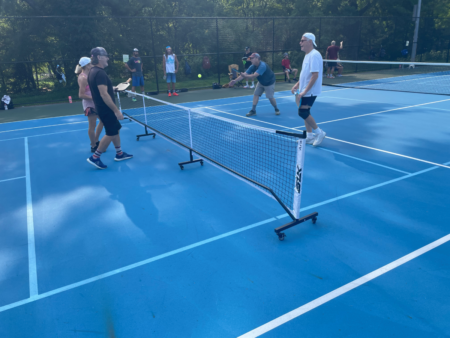 Pickle ball players around roll away net