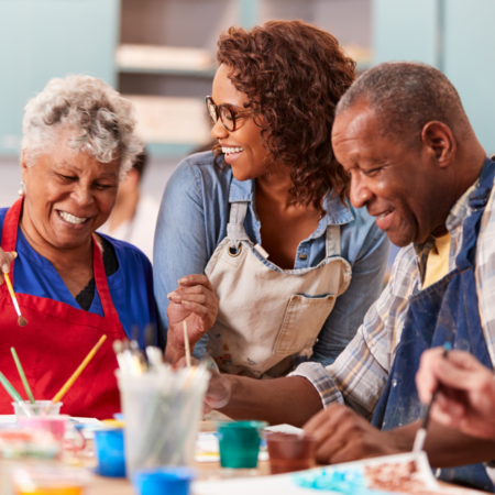 three senior citizens in a painting class wearing aprons