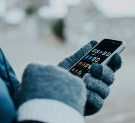 hands holding cell phone wearing gray gloves