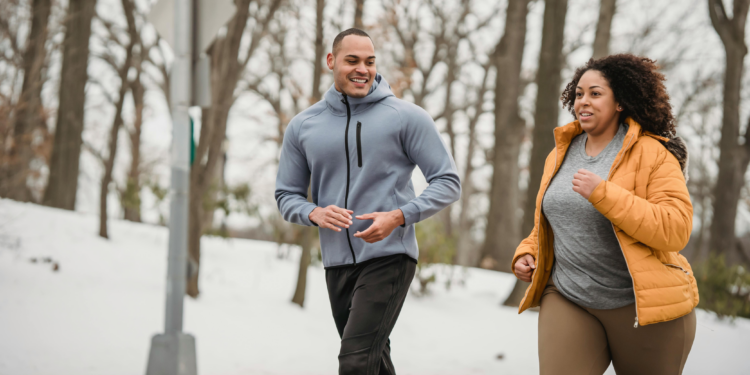 man and woman walking jogging in snowy forest